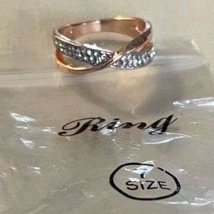 Gold colour ring with crisscross bands on top one gold & one with clear stones